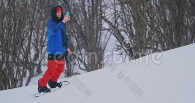 在滑雪坡滑雪时，使用智能手机拍摄风景图片